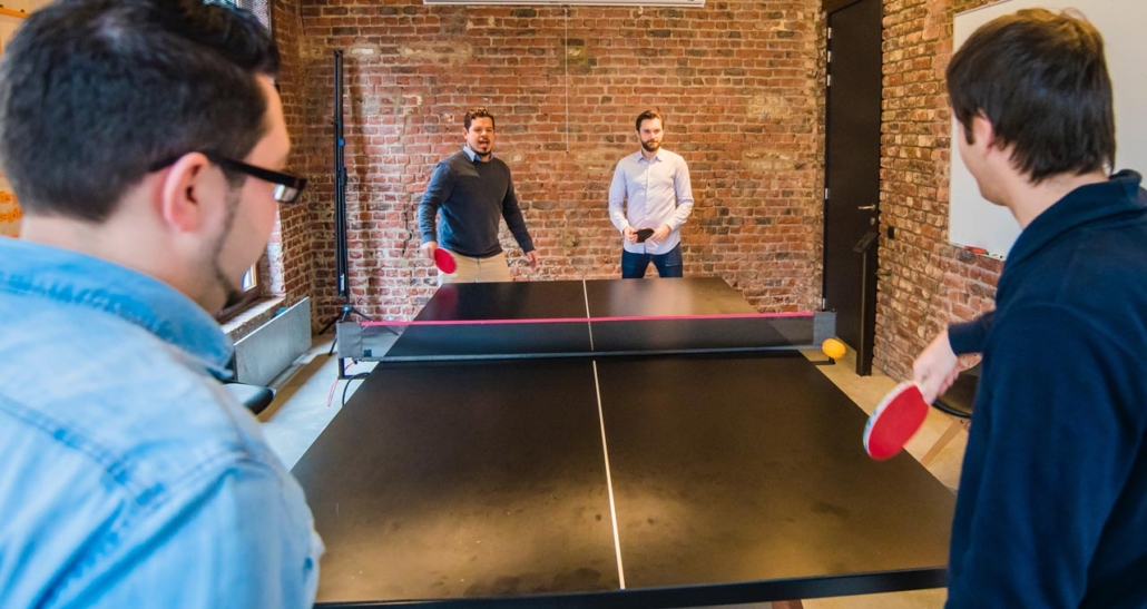 profissionais jogando ping pong área de convivência em empresas