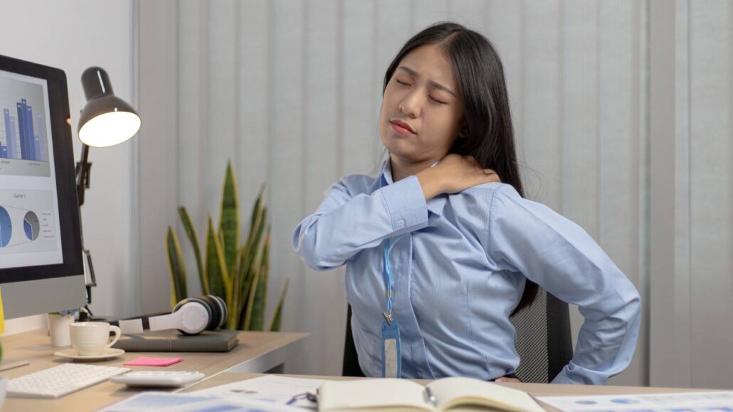 Mulher com dores lombares por falta de ergonomia.